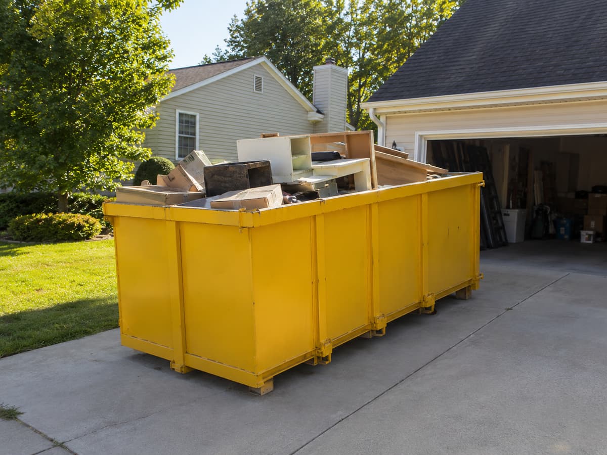 Residential Dumpster Rental in Bethlehem, PA — amber dumpster on a residential driveway loaded with household and yard waste