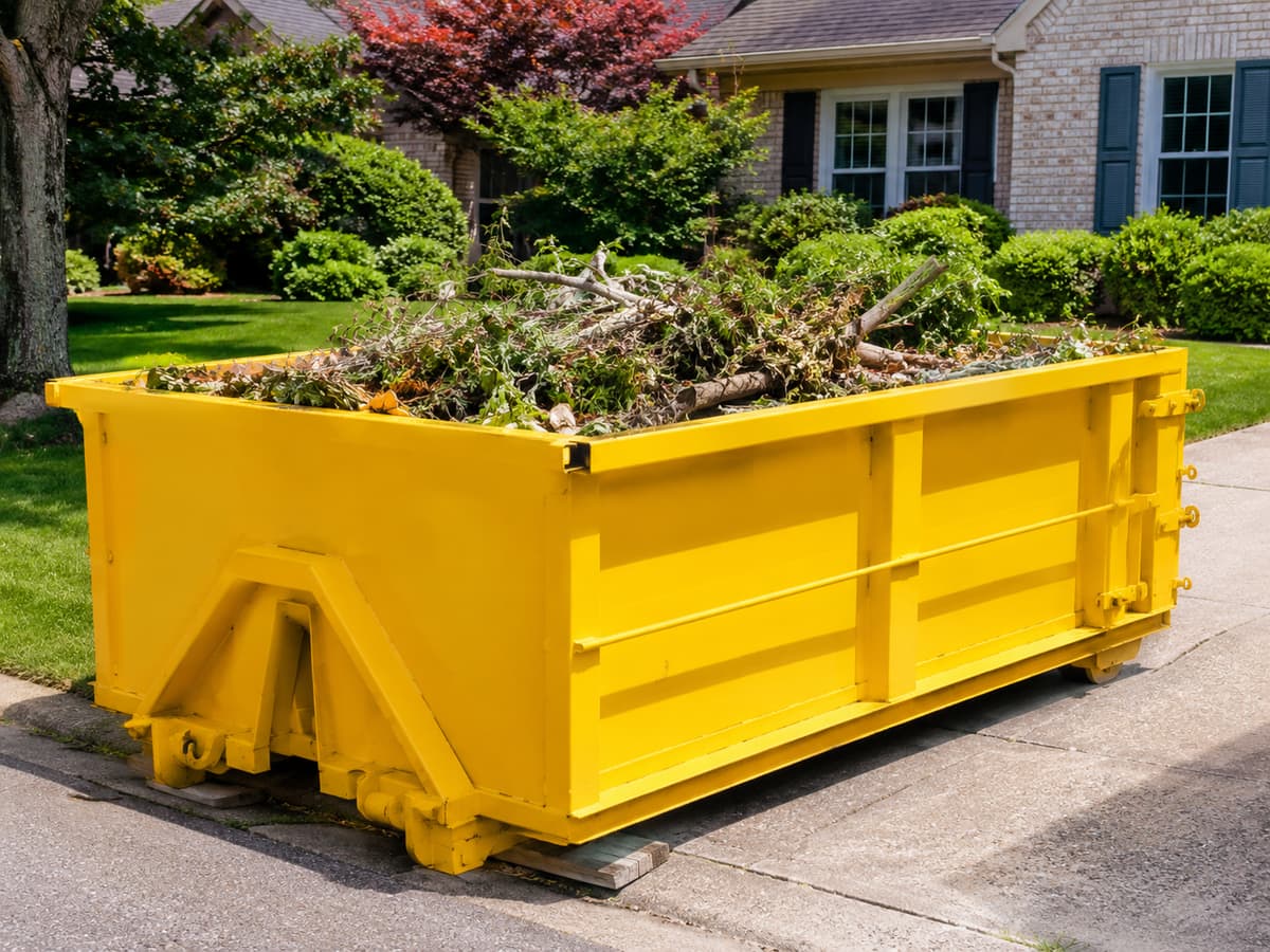 Residential Dumpster Rental in Macungie, PA — amber dumpster on a residential driveway loaded with household and yard waste